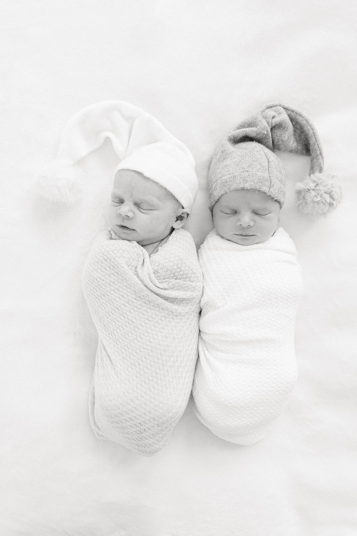 Black and white photo series of sleeping newborn twins swaddled in white blankets lying side by side on soft bedding.