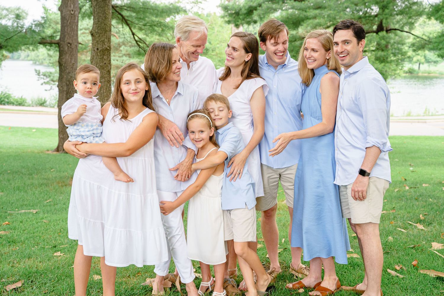 Extended family wearing coordinated blue and white outfits poses together in a park setting.