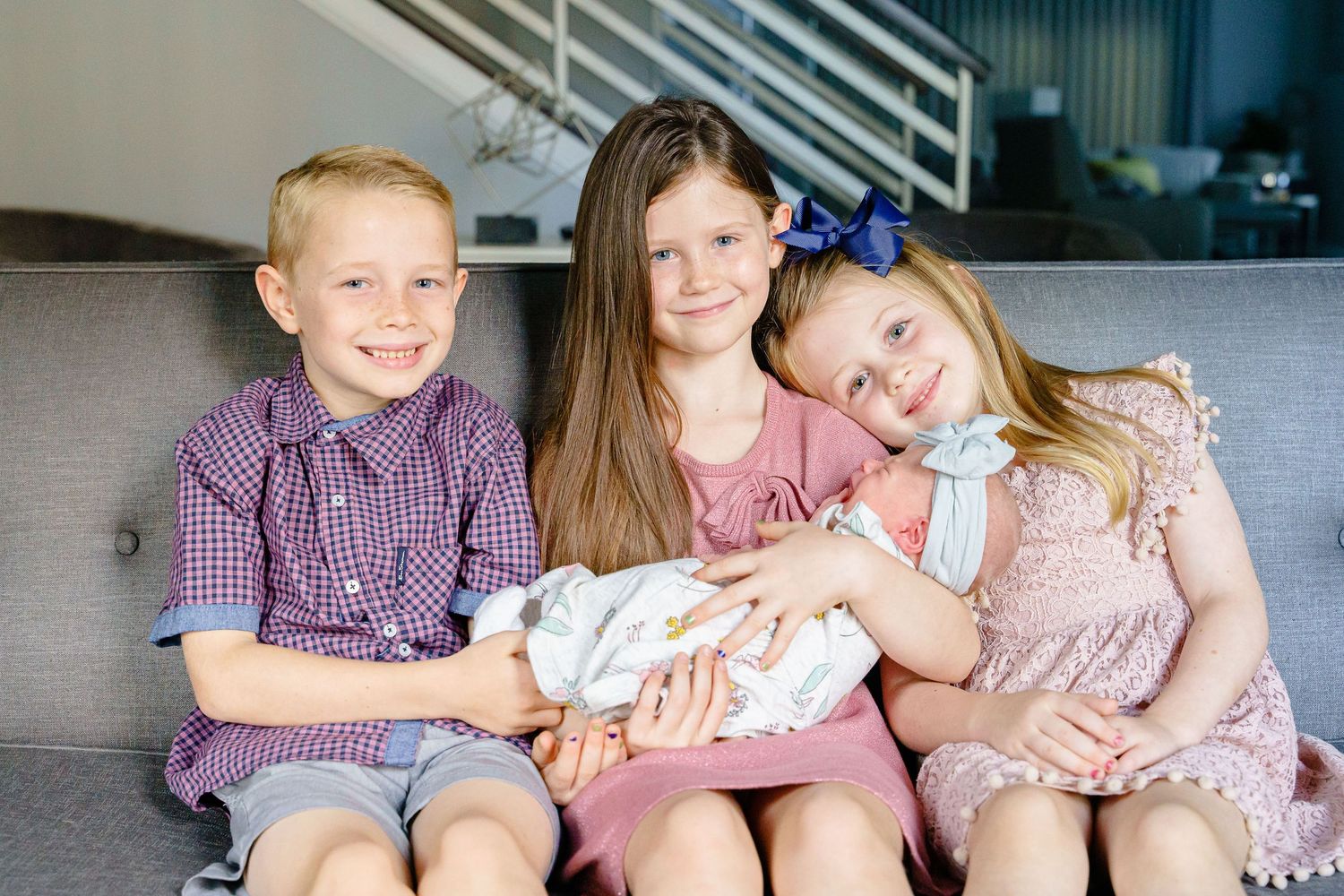 Family group wearing coordinated purple and pink outfits sitting together on a couch.