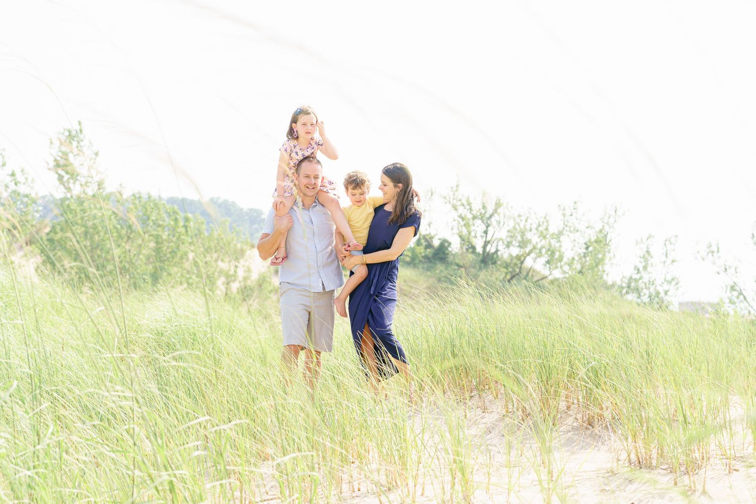 A couple shares a tender moment together in a sunlit field of tall grass.