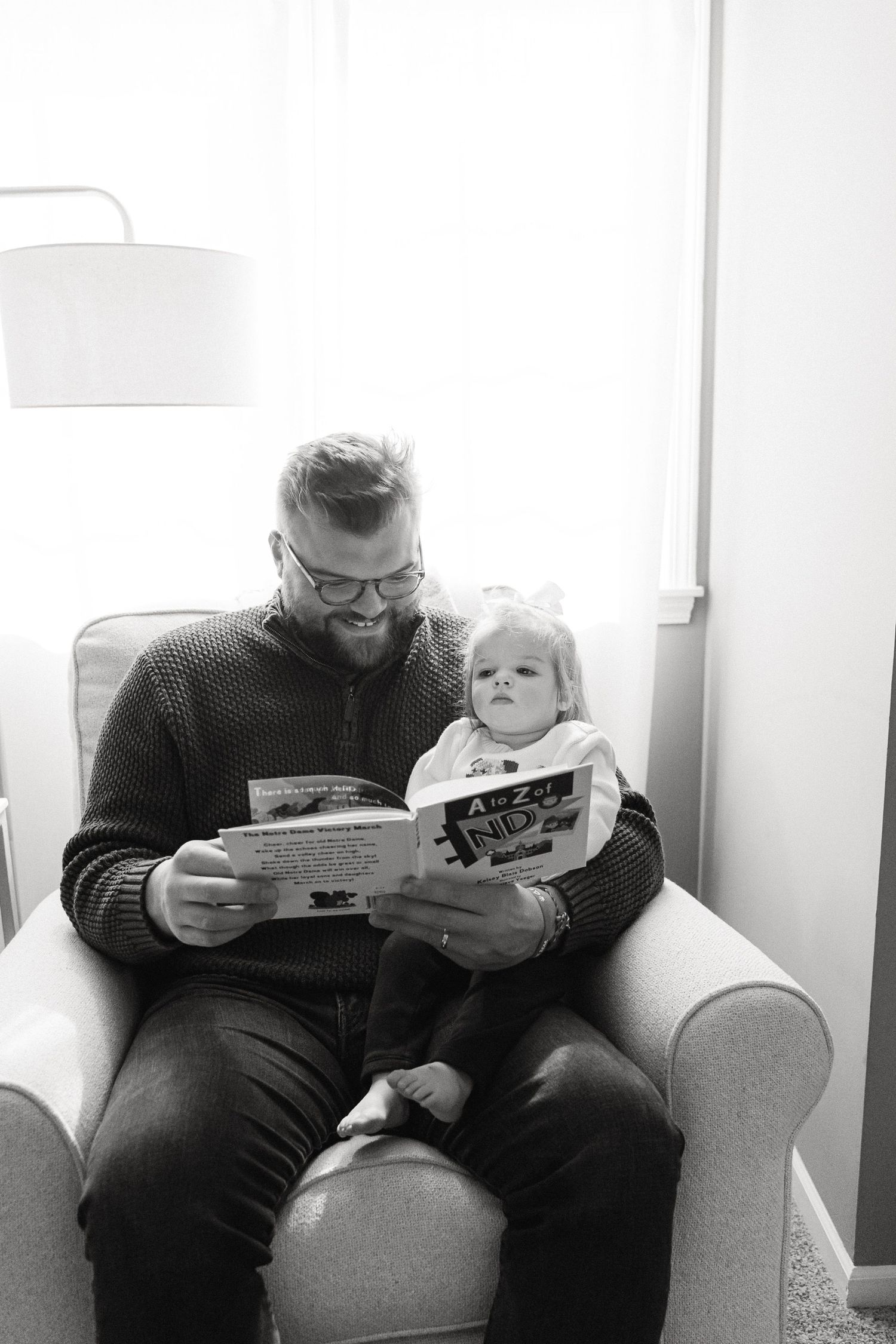 A series of three black and white photos showing a person reading a book to a small child on a couch.