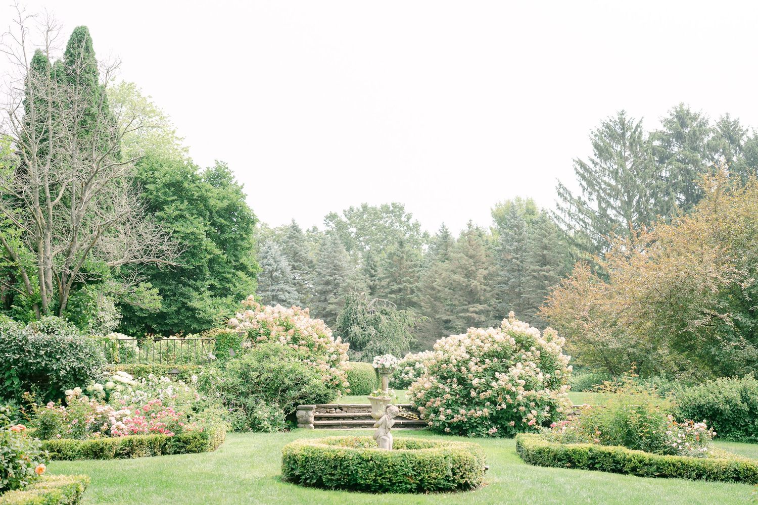 A scenic panoramic view of a lush green garden landscape with trees and shrubs stretching across multiple frames.