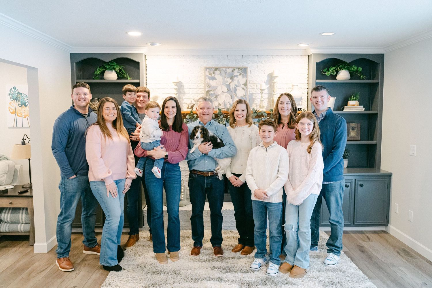 Group of people in casual attire standing together in a white modern interior space during a gathering.