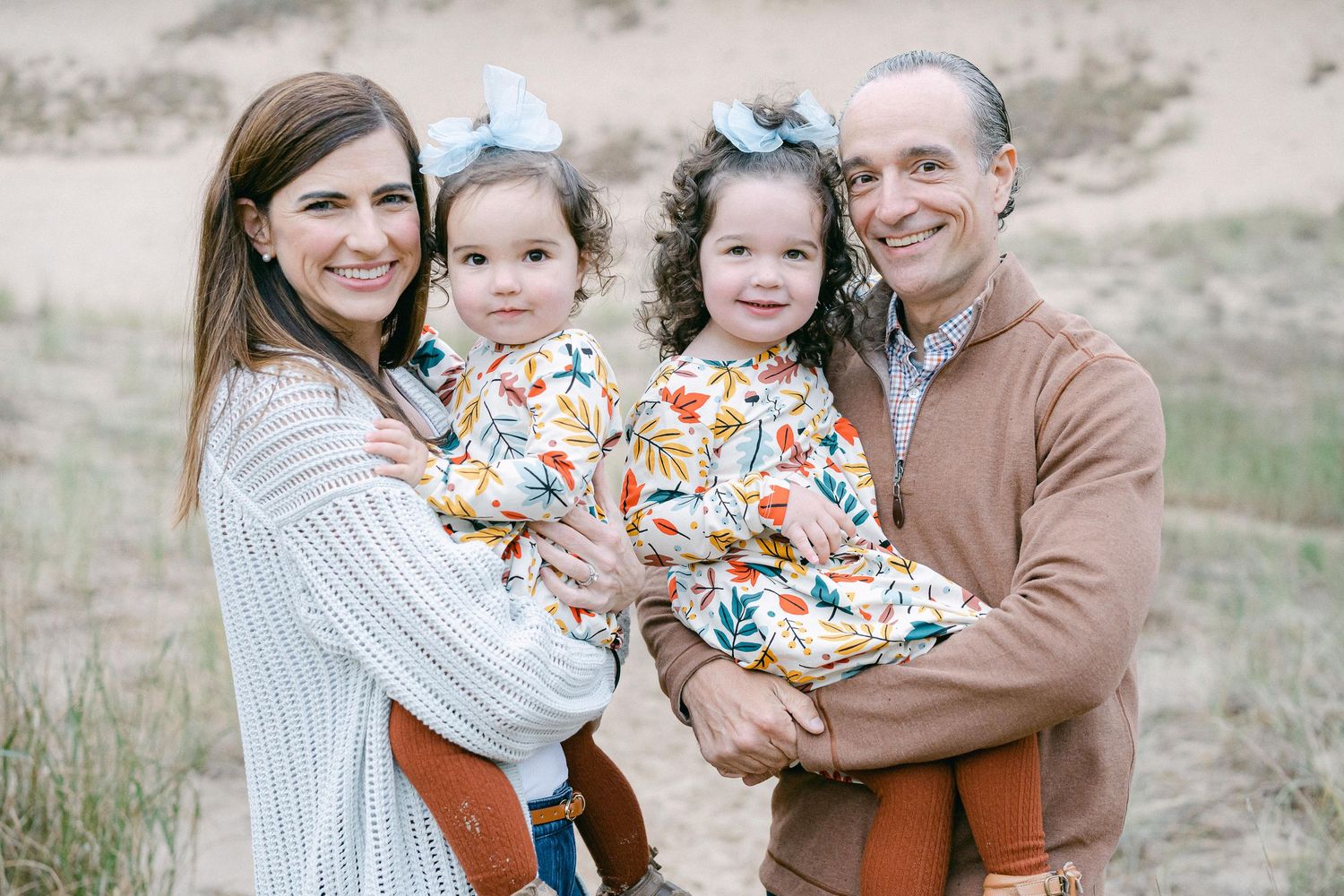 A family in coordinating autumn outfits poses together outdoors in a natural setting during a photo session.