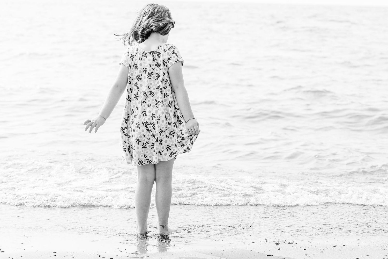 A black and white beach portrait captures figures walking along the shoreline.
