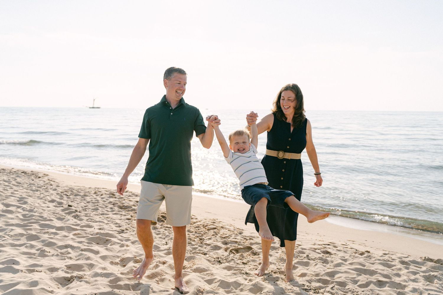 Family walking and playing together on a sandy beach at sunset by the ocean.
