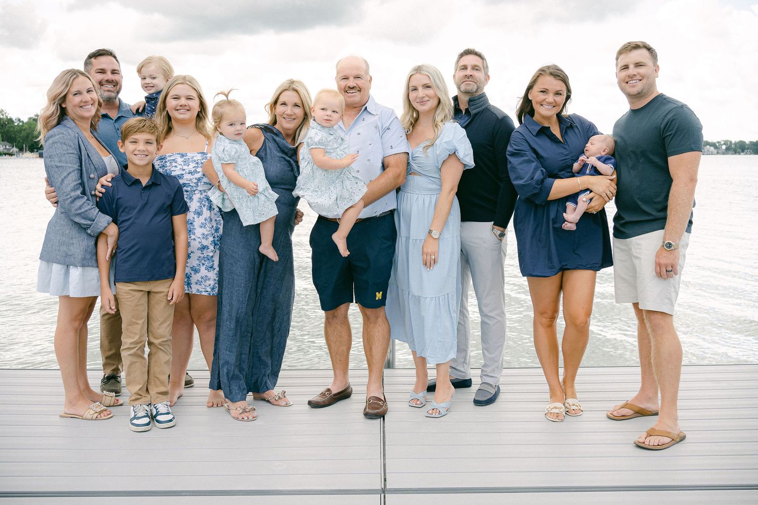 A group of people wearing coordinated blue and white outfits pose together on a beach at sunset.