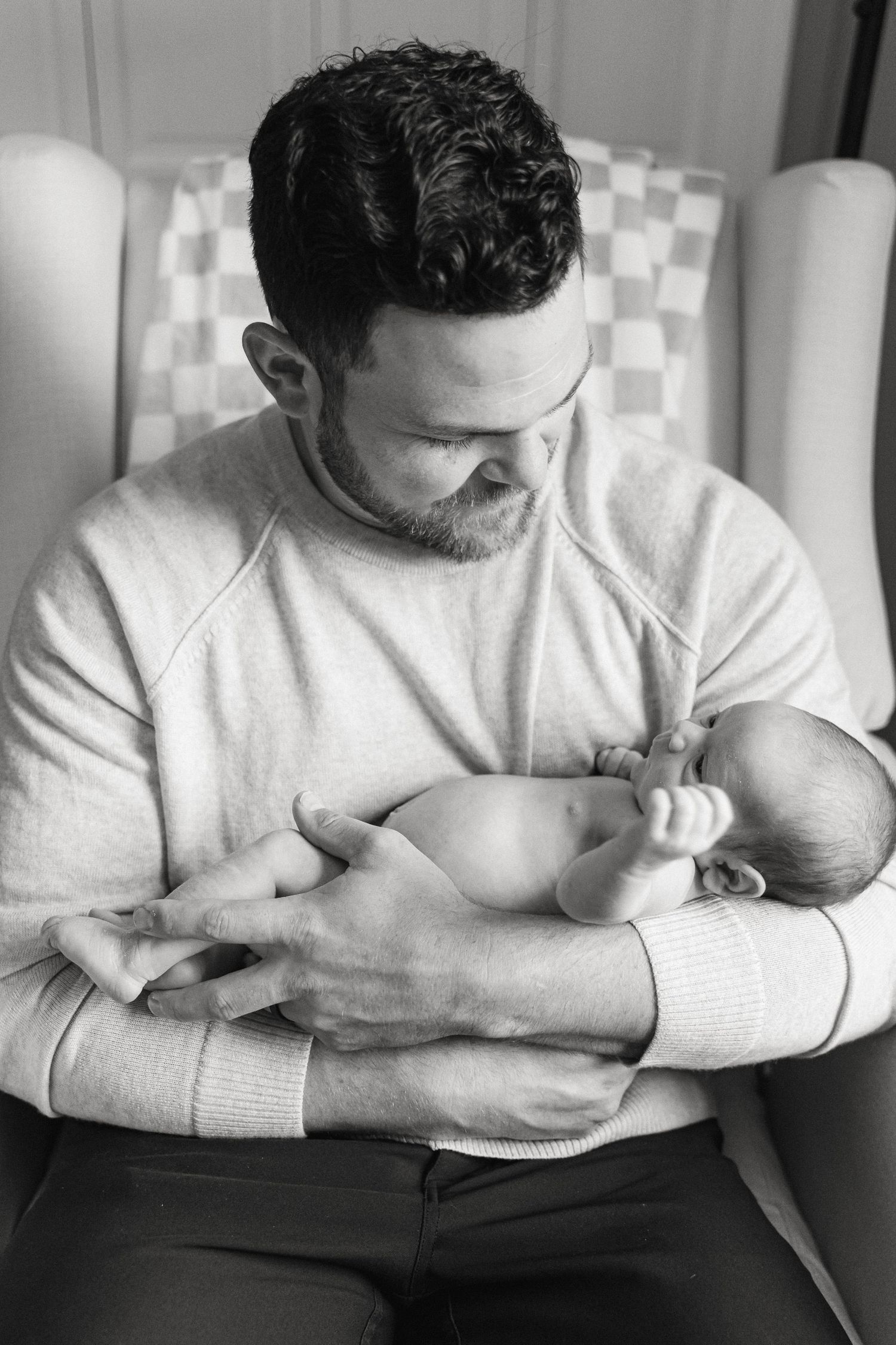 Black and white photos showing tender moments of a parent holding and feeding a newborn baby.