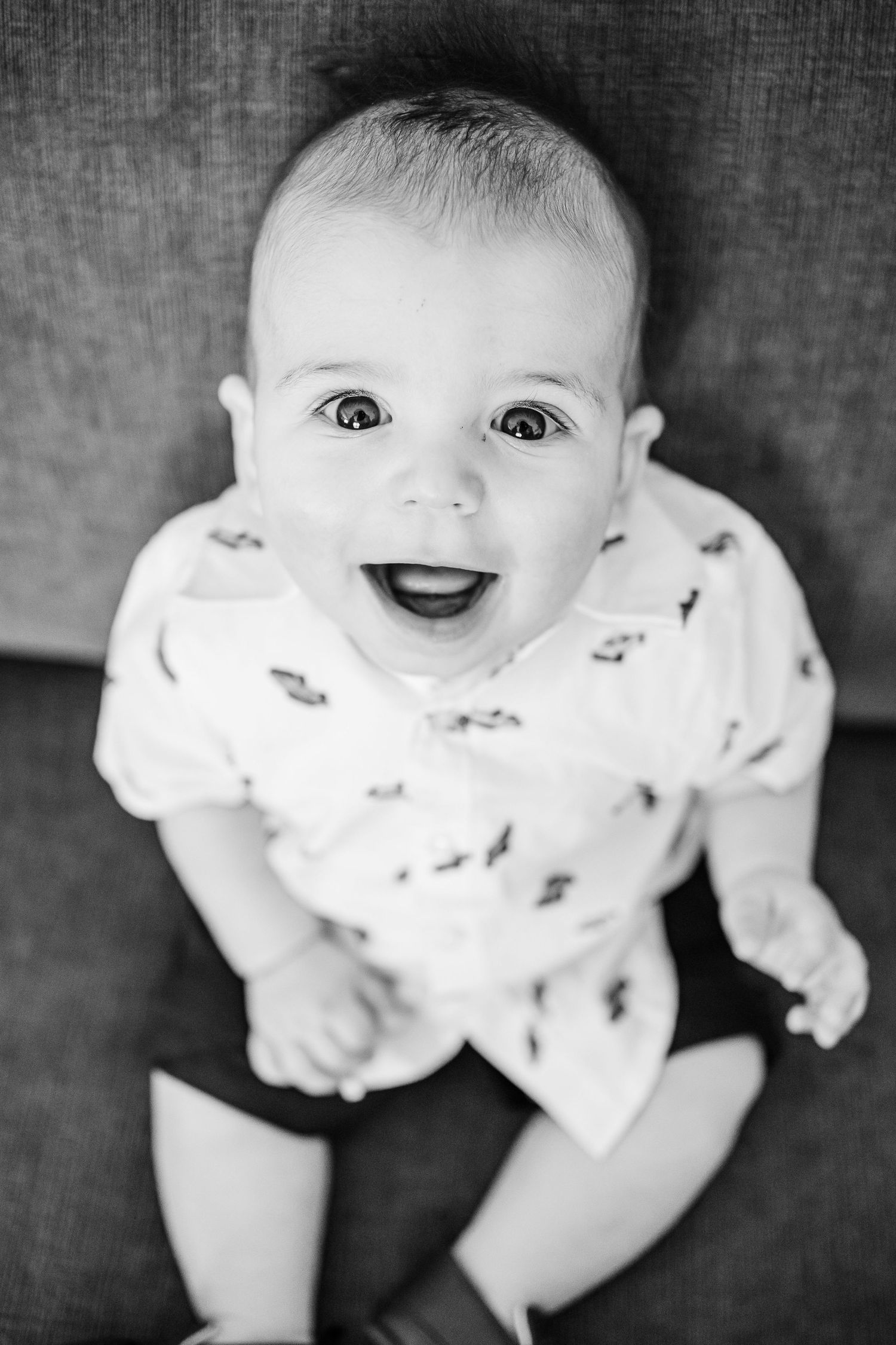A series of black and white photos showing a baby lying down and making various playful expressions.
