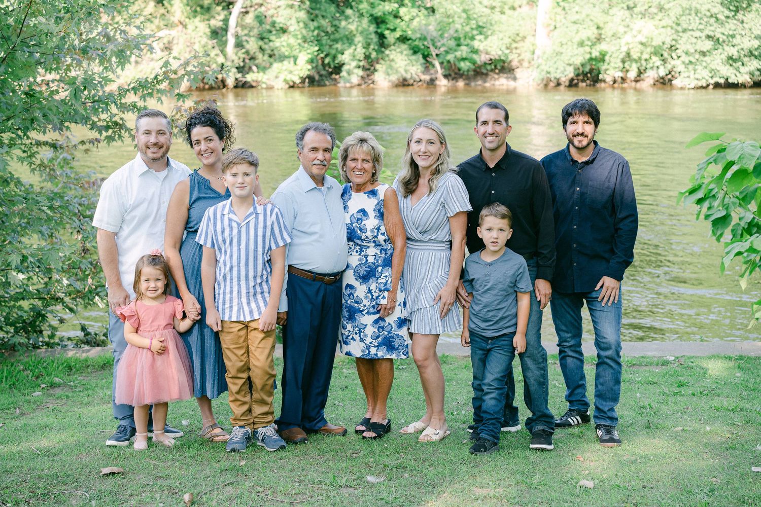 A series of outdoor family portrait photos taken near a river with lush greenery in the background.