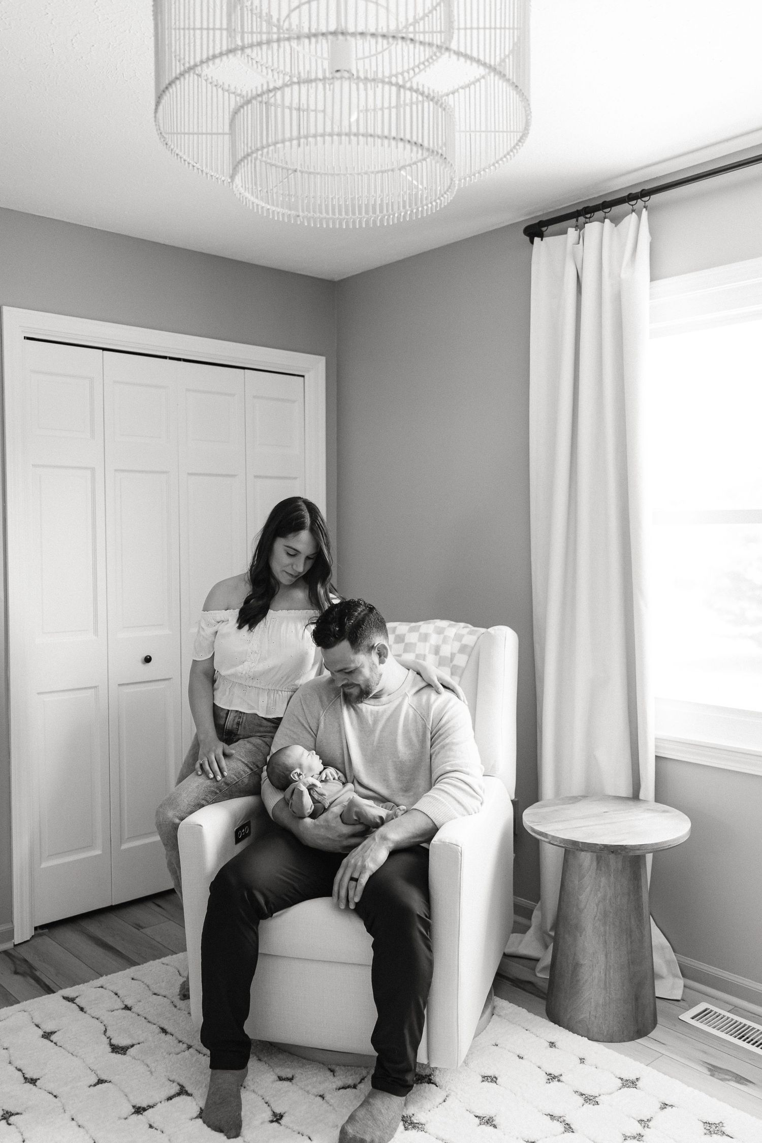 Black and white photo series showing tender moments on a white couch in a minimalist room with natural lighting.