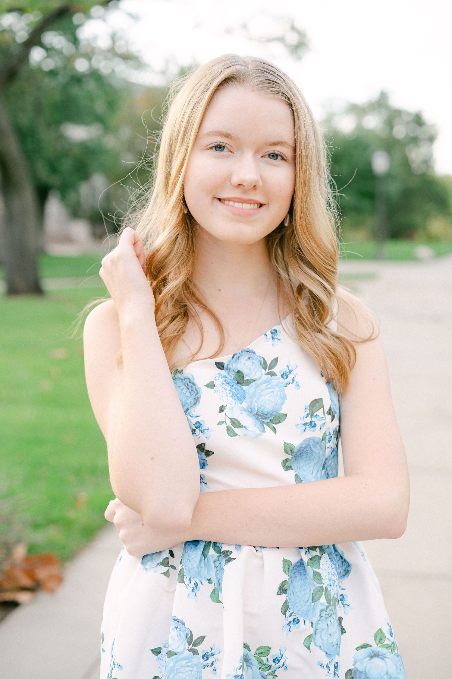 A floral summer dress with blue blooms is featured in an outdoor portrait session on a sunny day.
