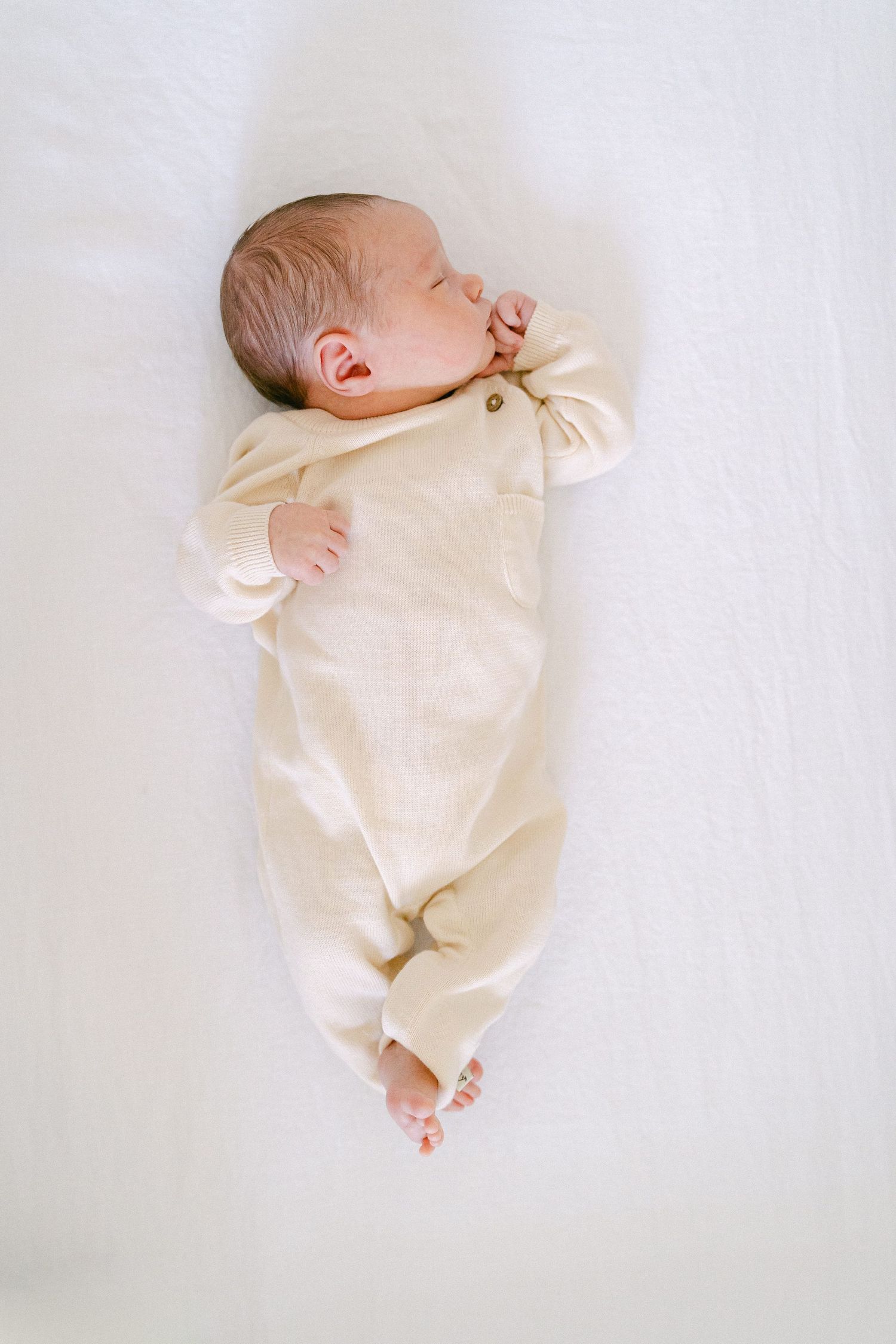 Newborn baby wearing cream colored clothing photographed from different angles on white background.