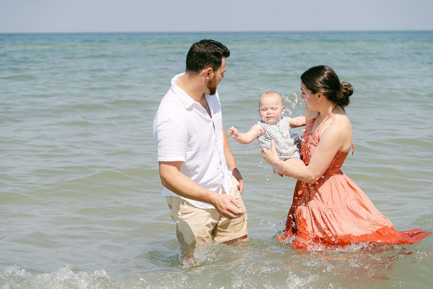 A series of beach photos showing a family playing and splashing together in the ocean waves.