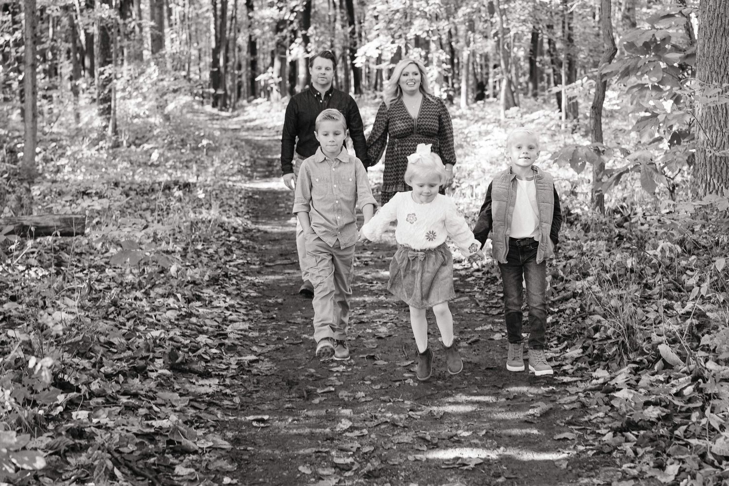 A group walks together along a wooded path during a nature hike in black and white photography.