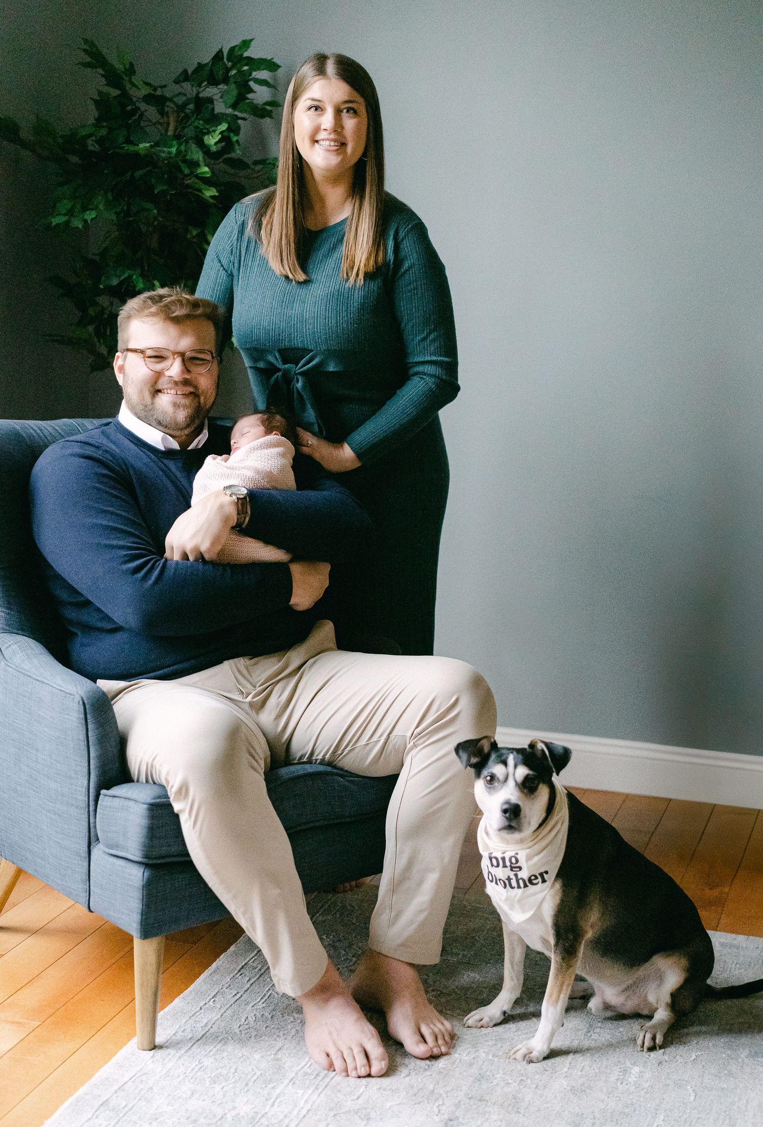 A couple sits on a grey couch with their black and white dog in a series of casual indoor photos.