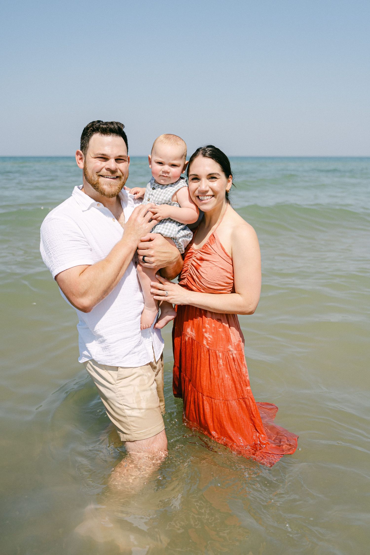 Family enjoying a playful moment together in the ocean waves wearing summer attire.