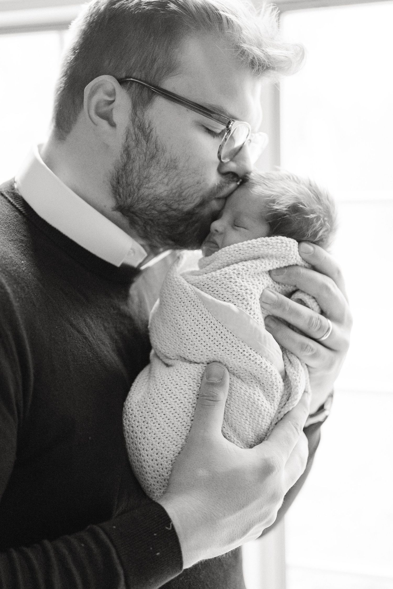 A series of tender black and white photos showing intimate moments with a swaddled newborn.