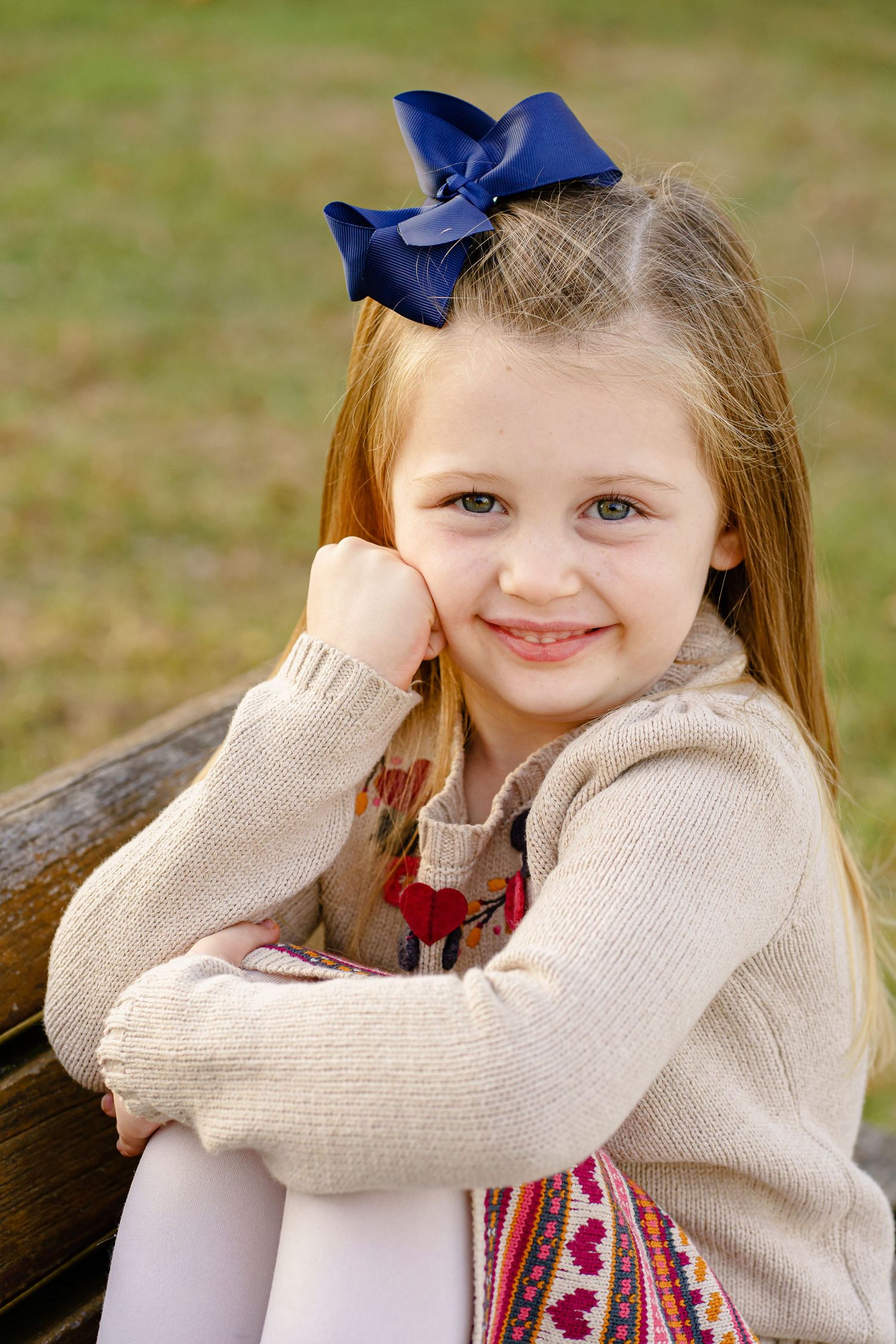 A series of photos showing someone wearing a cream sweater and navy blue bow against a blurred outdoor background.