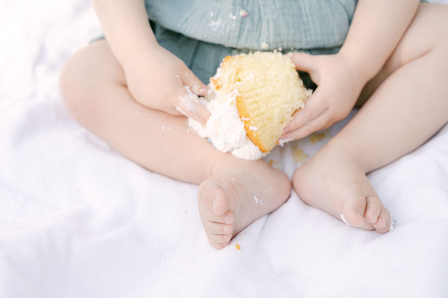 Close-up of baby's bare feet against a white background with a small orange citrus fruit nearby.