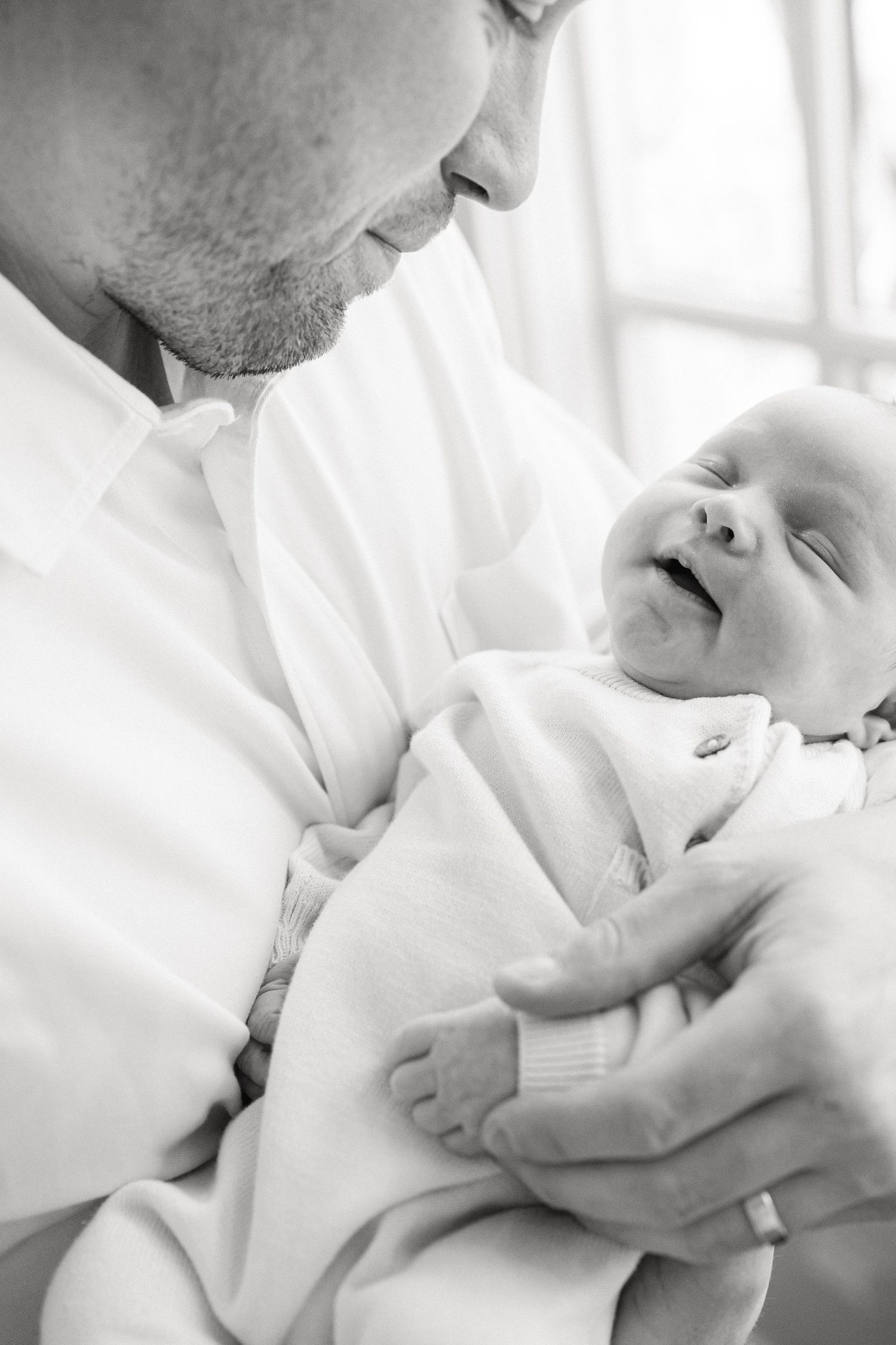 A tender black and white photo series showing intimate moments between a parent and newborn baby.