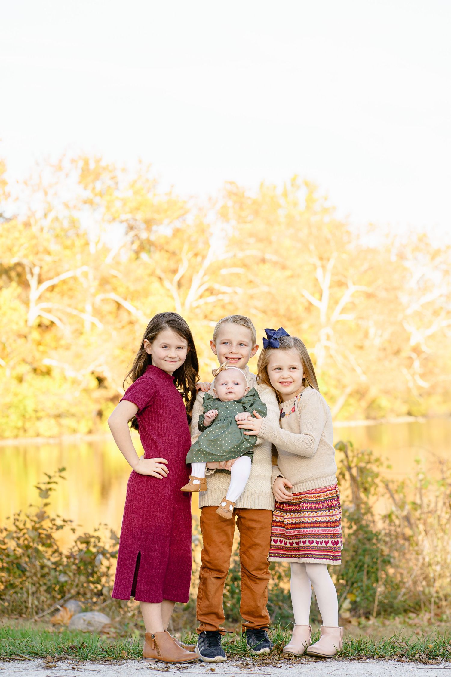 Children playing and hugging outdoors in autumn with golden sunlight and trees in the background.