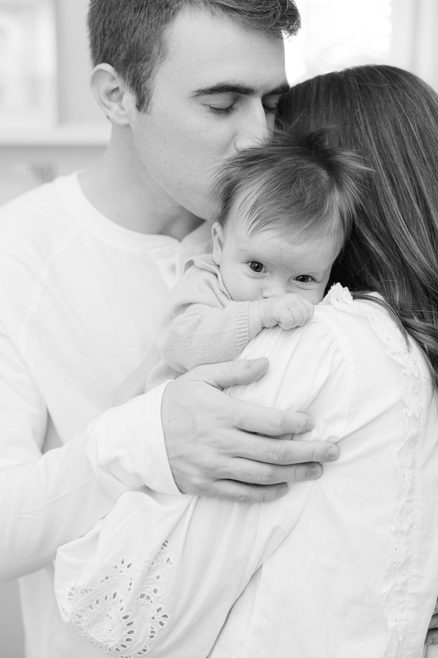 Series of intimate black and white photos showing tender moments with a baby in white clothing.