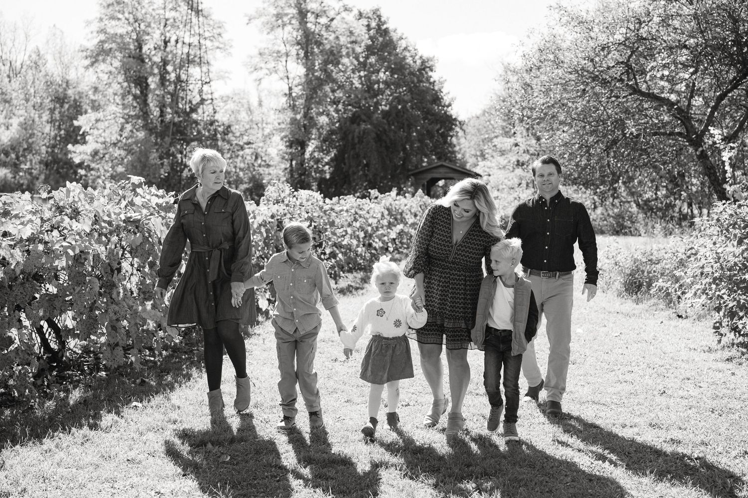 A sequence of black and white photos showing people walking together through a park or garden setting.