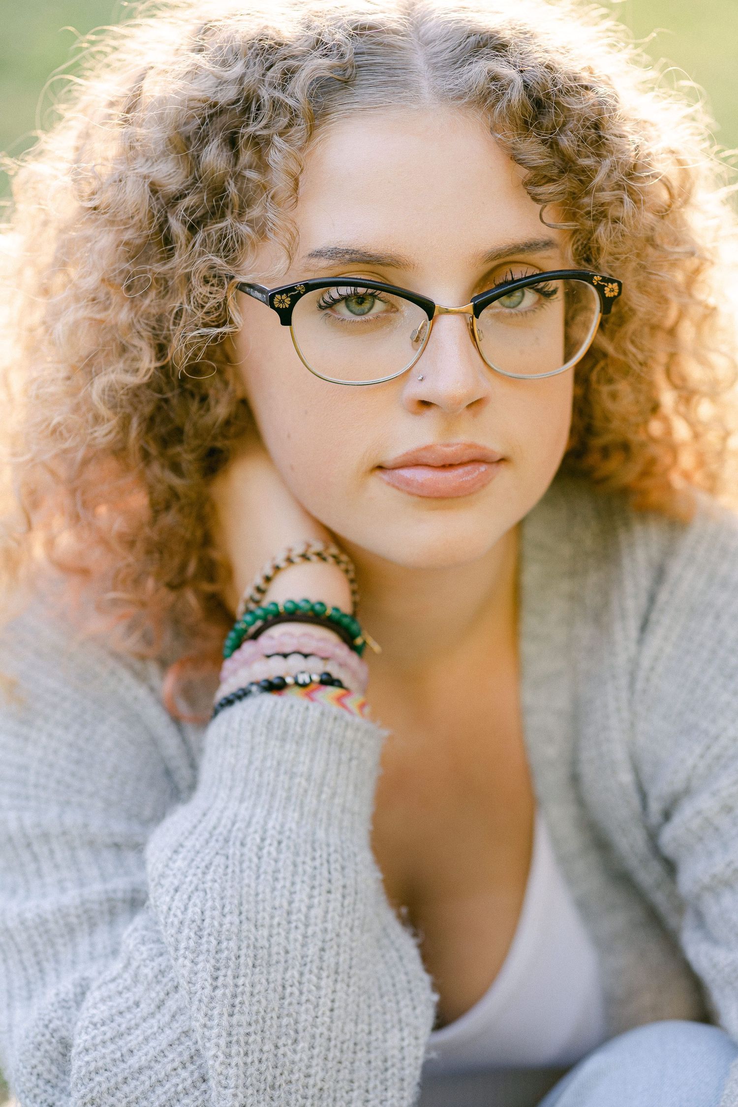Close-up portrait showing curly hair and glasses with natural lighting creating a soft glow effect.