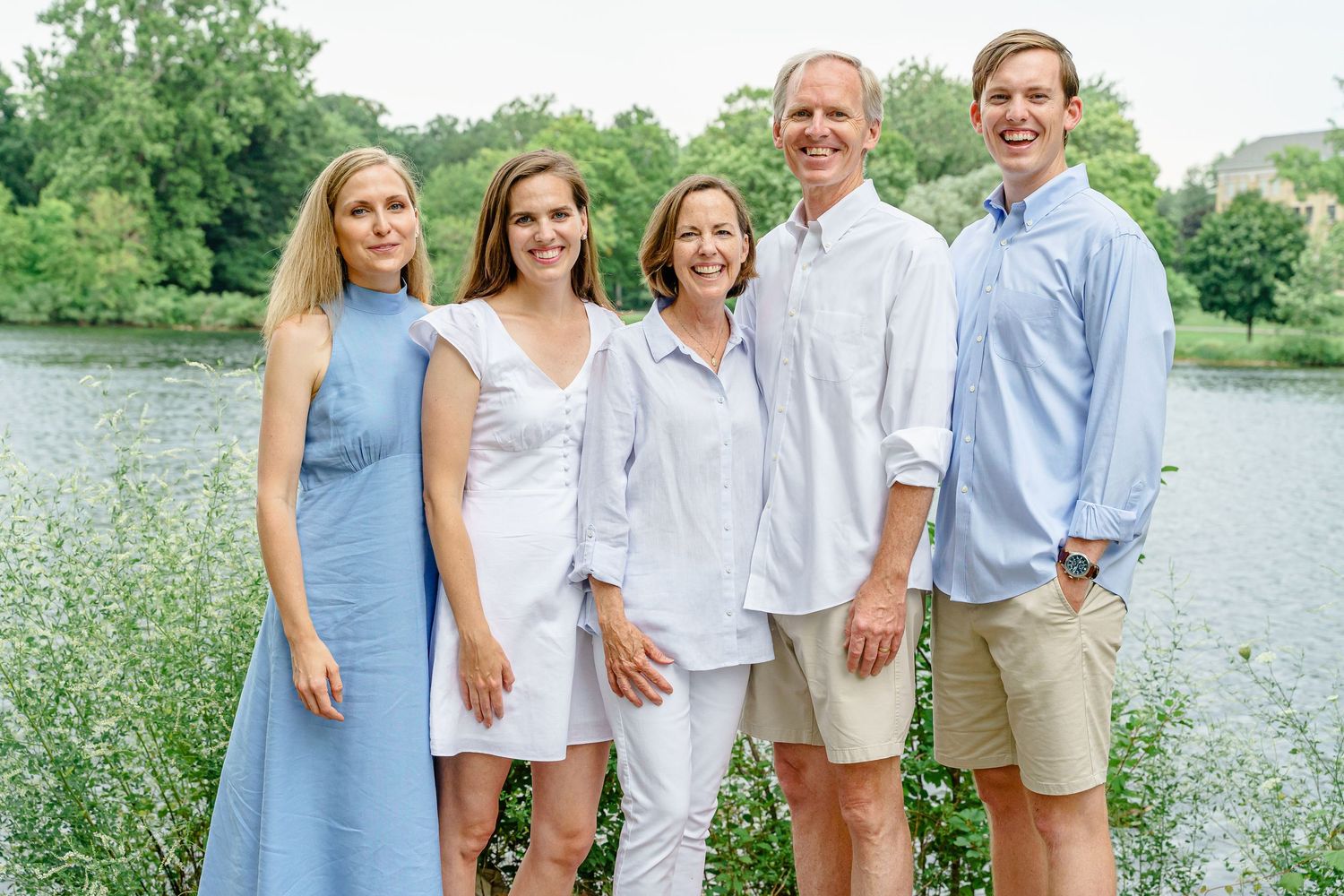 Five people pose together outdoors wearing coordinated blue and white outfits near a lake.