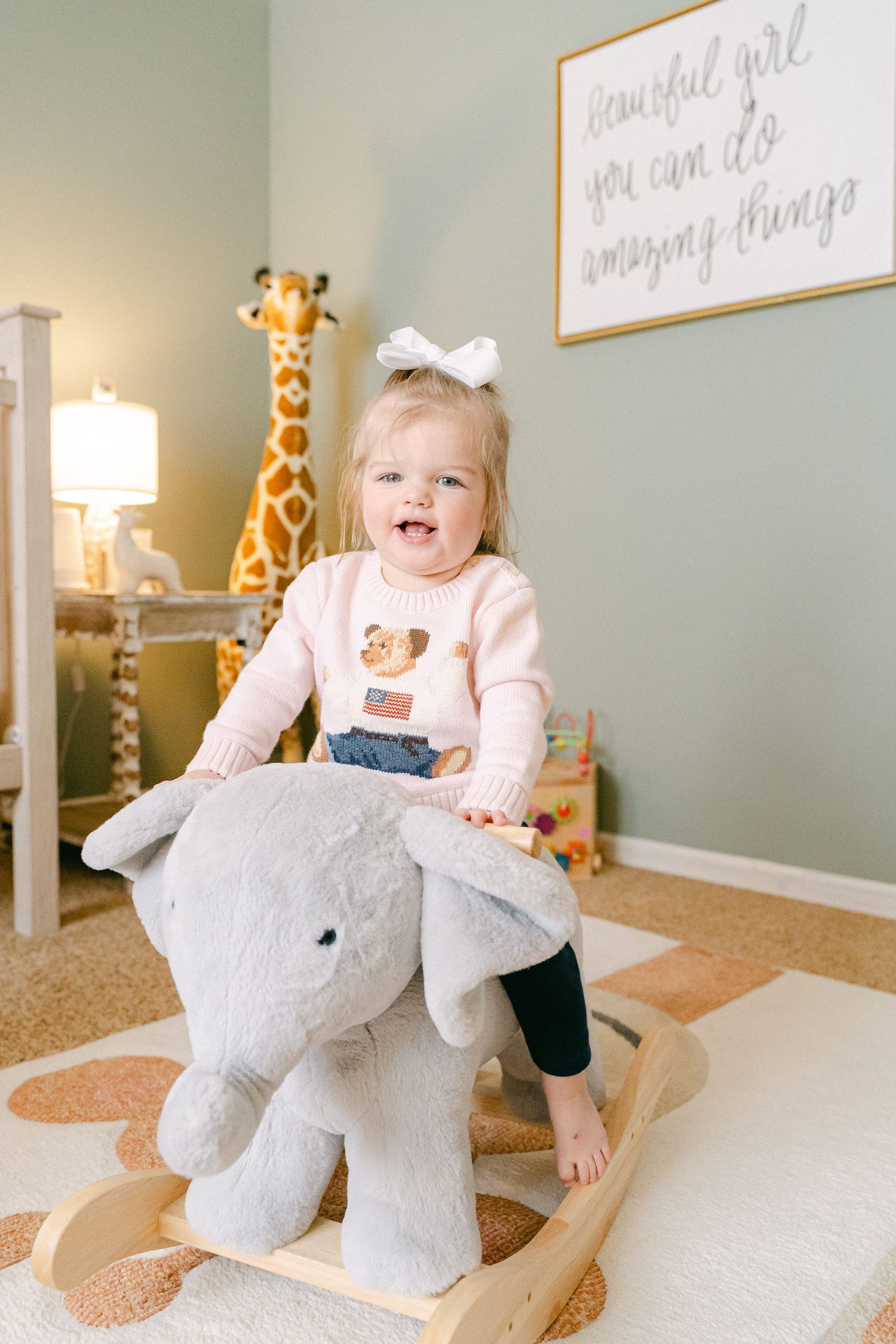 Plush elephant rocker toy in nursery room with soft gray walls and decorative wall art.