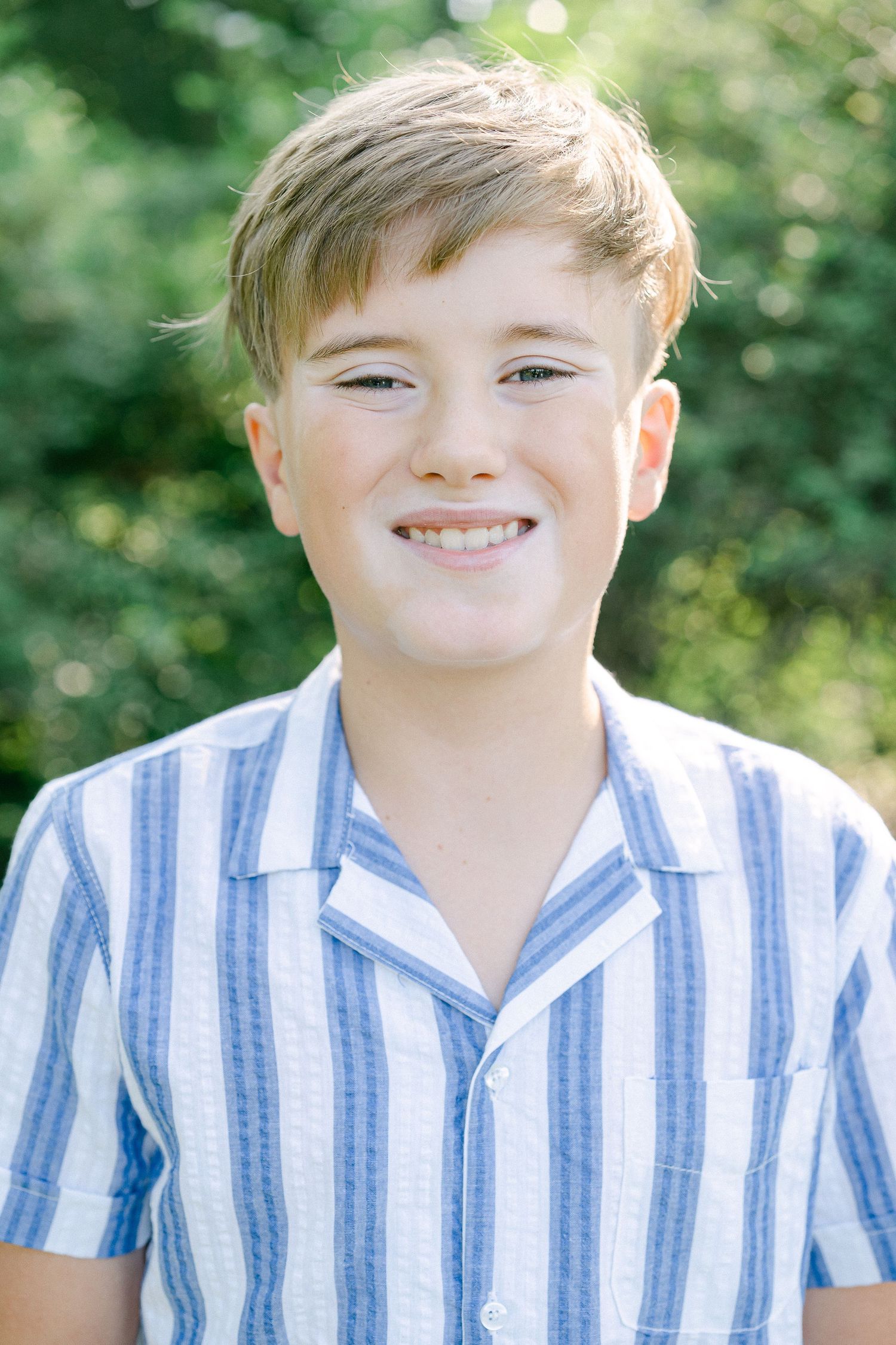 A series of four close-up outdoor portraits showing a child in a blue and white striped collared shirt.