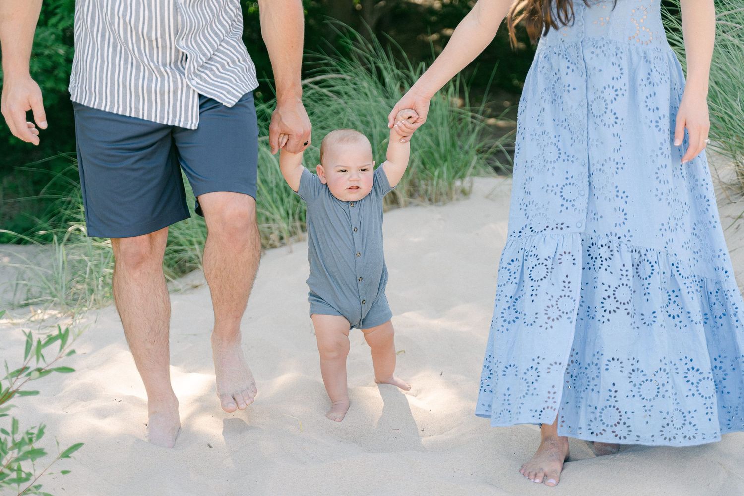 Family walking together on a sandy path surrounded by greenery in coordinated blue and white outfits.