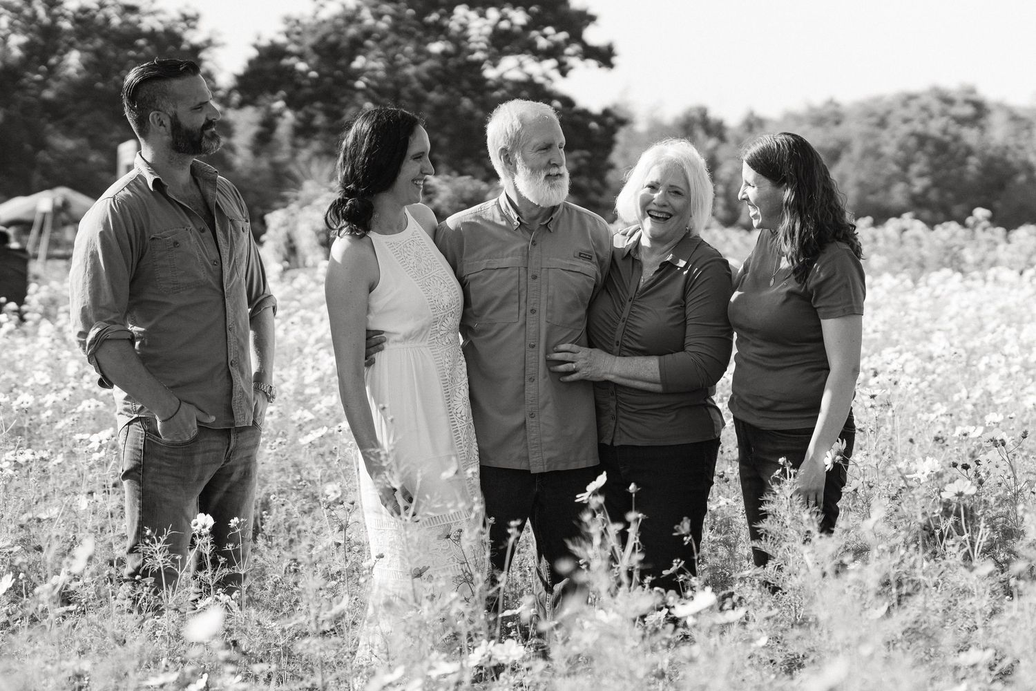 Group of people standing in a line outdoors in a wildflower meadow on a sunny day.