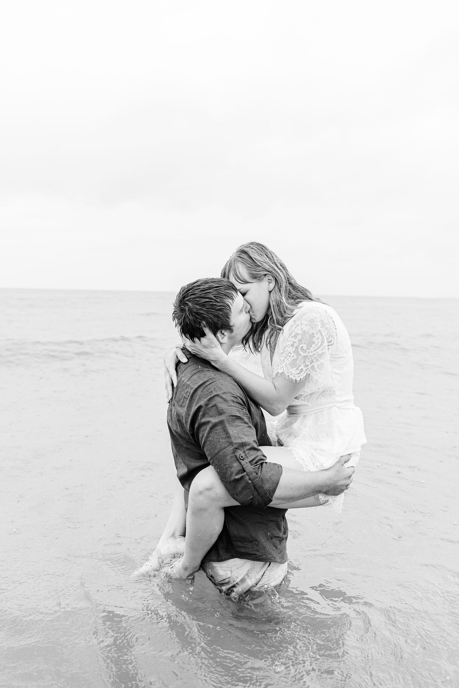 A romantic sequence of black and white photos shows a couple embracing in the ocean waves.