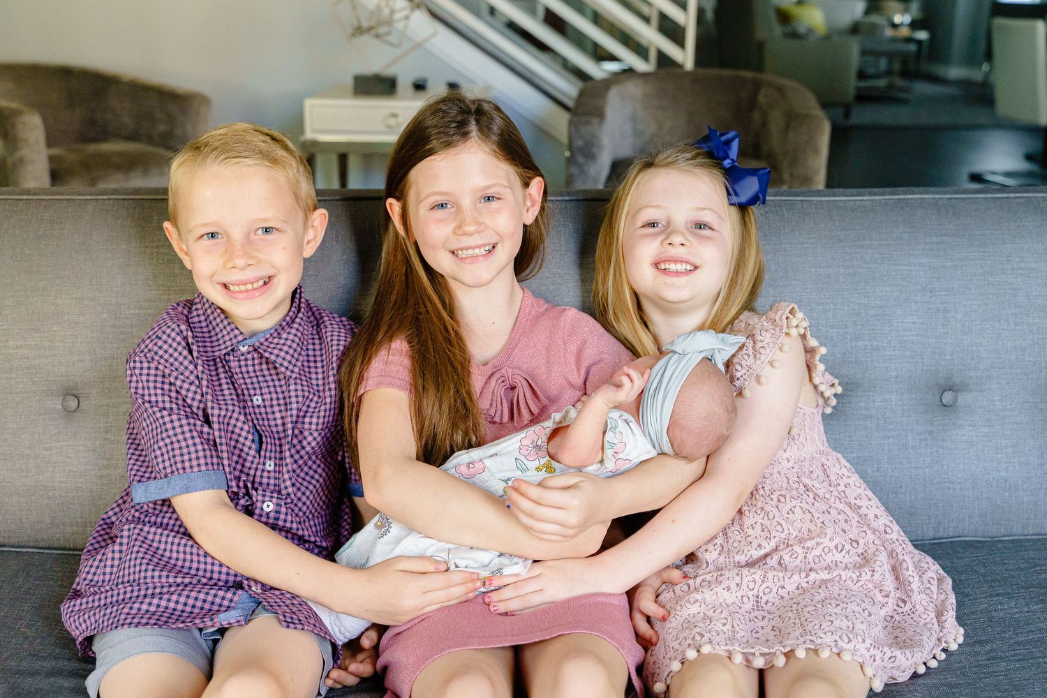 Four children sitting together on a wooden bench outdoors.