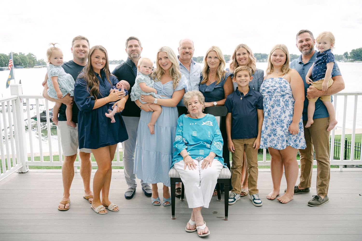 Group photo of family members lined up and smiling on a white wooden deck by the water.