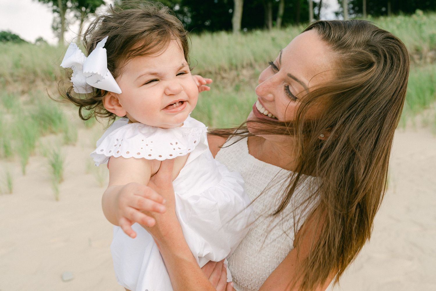 A parent and child share joyful moments together on a sunny day at the beach.