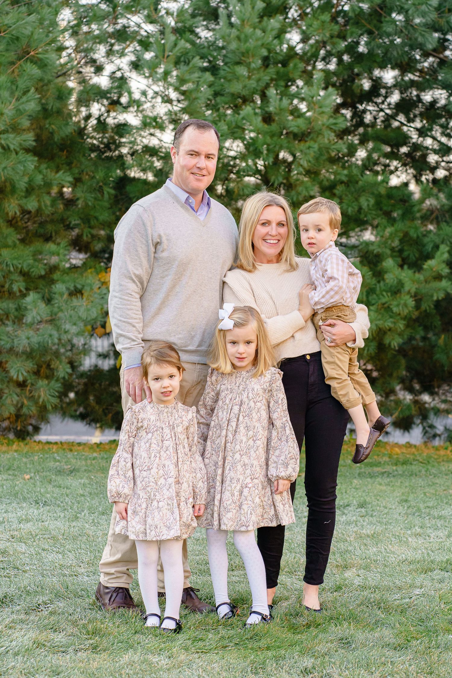 Family portrait session in a park with matching outfits and natural greenery backdrop.