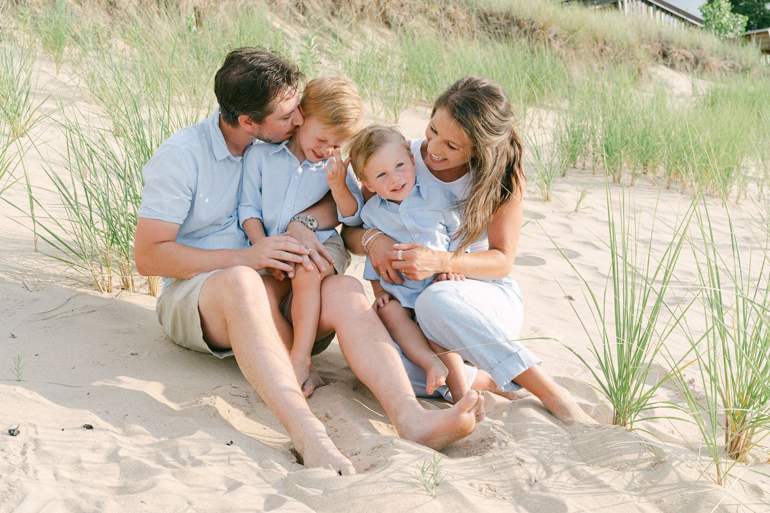 A family sits together on a sandy beach during a sunny day, enjoying quality time outdoors.