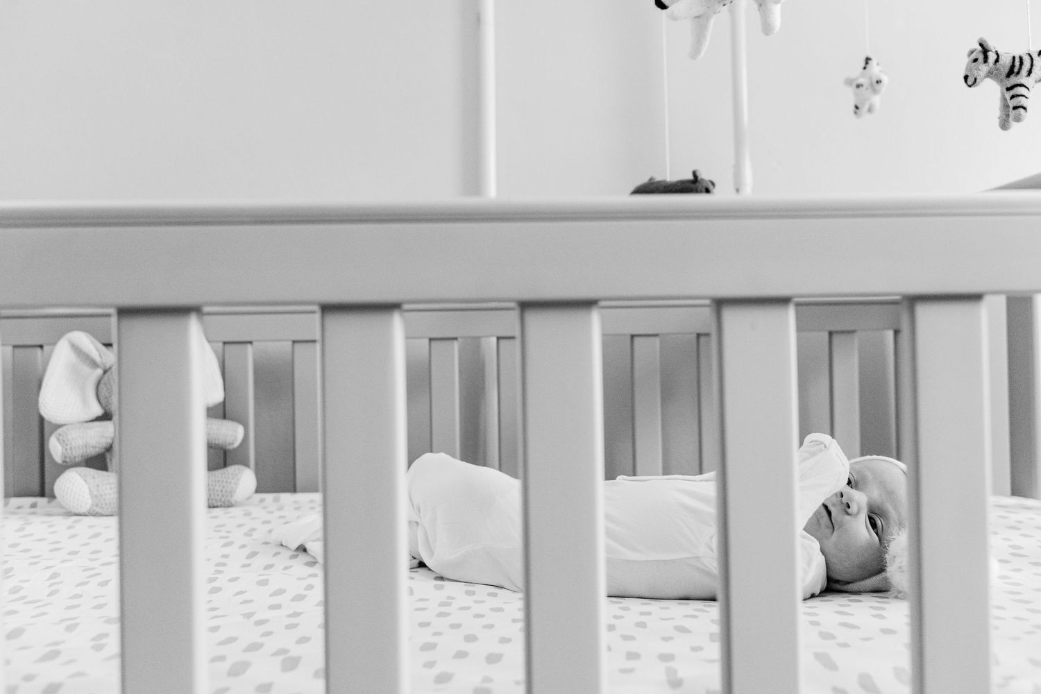 White crib and nursery furniture arranged in modern minimalist style bedroom.