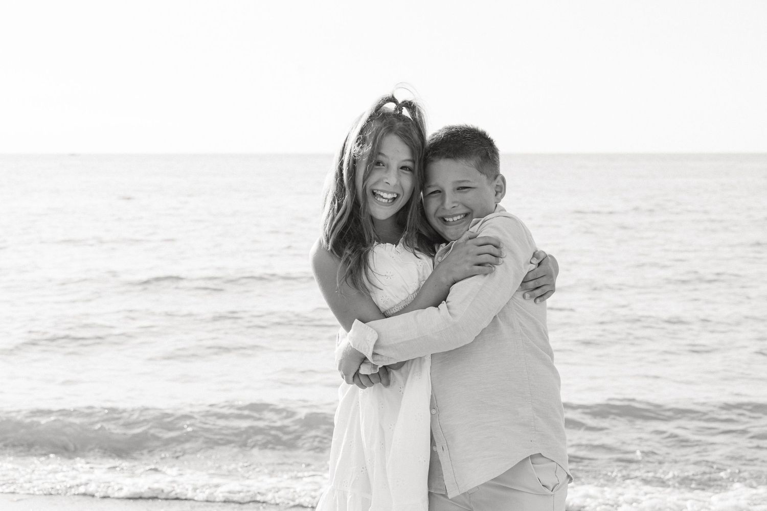 Candid black and white beach portraits with ocean horizon in background.