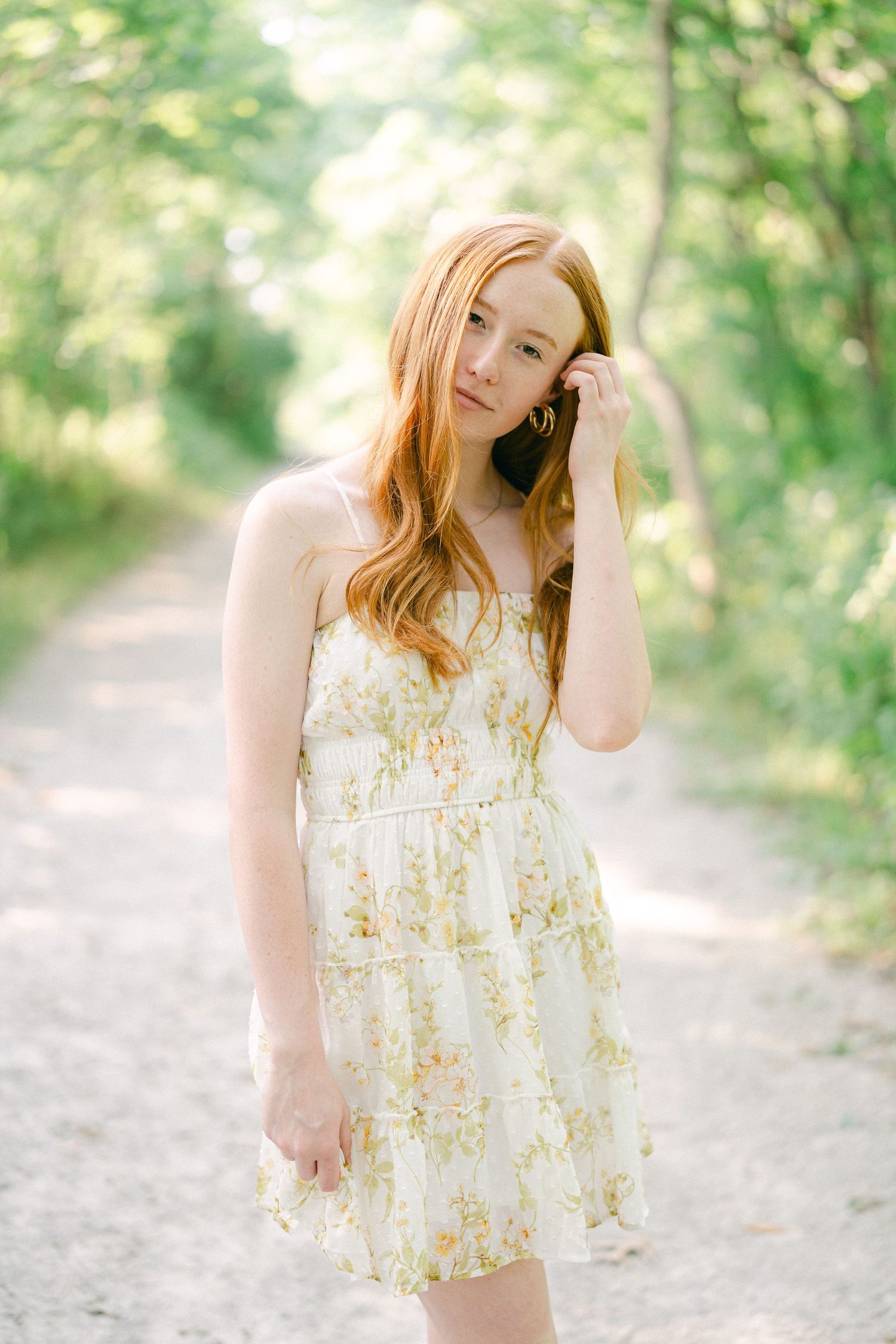 A dreamy portrait on a dirt path with soft lighting and natural greenery in the background.
