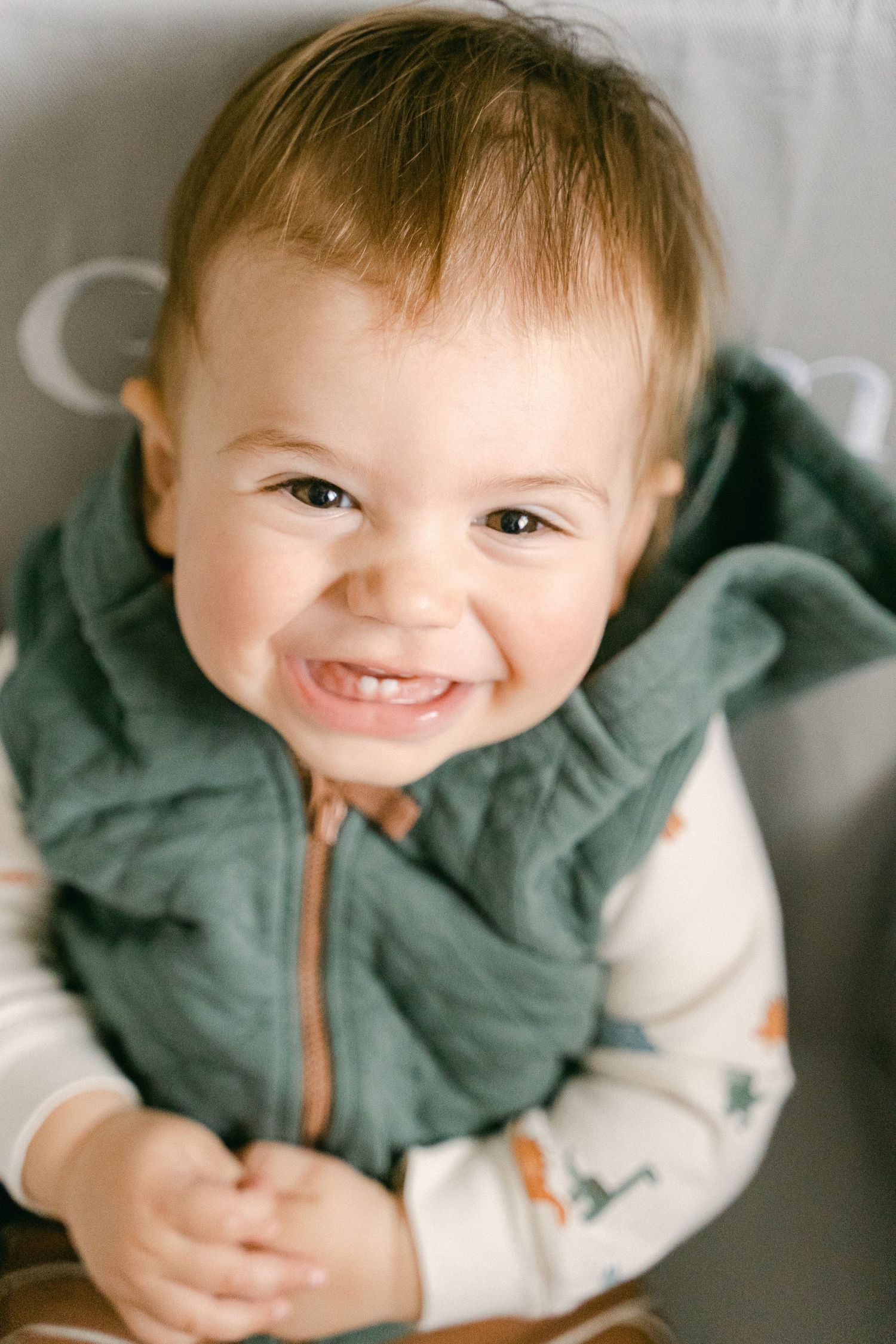 Close-up shots of a baby in a green hoodie showing happy expressions and smiles.