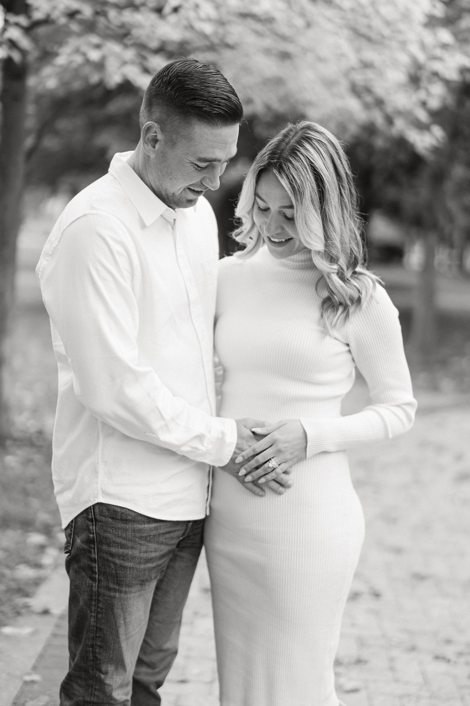 Intimate maternity photo session in black and white showing tender moments between couple.