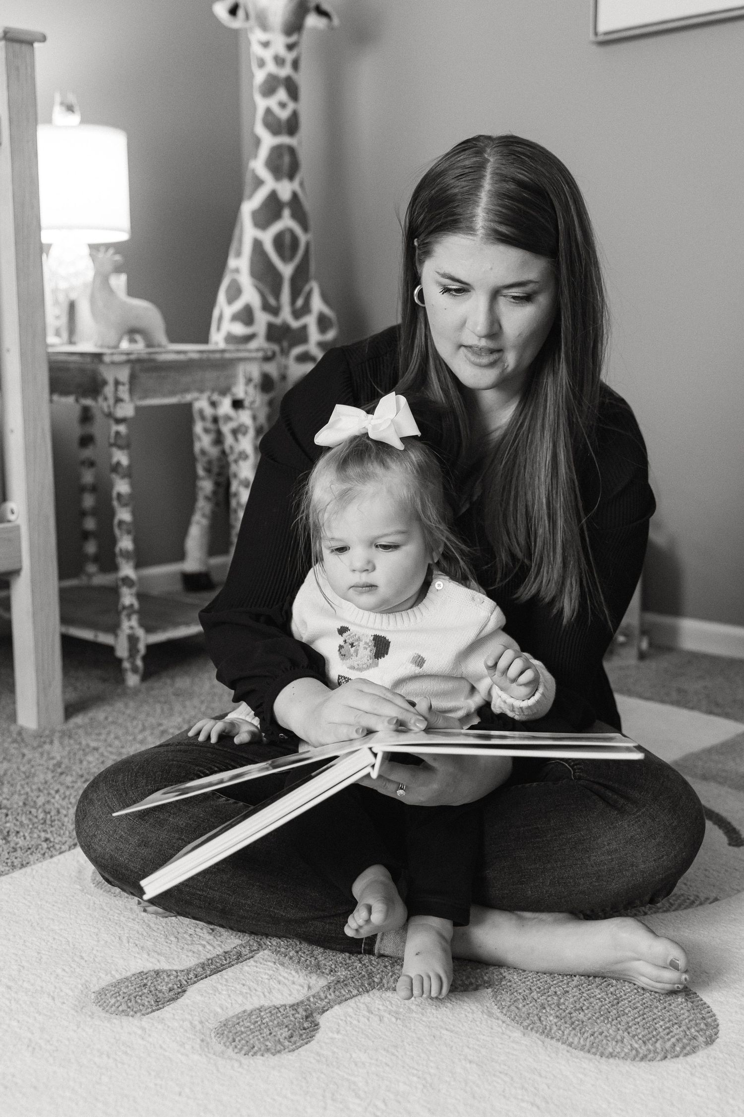 A series of black and white photos showing a parent and child reading a book together on a carpeted floor.