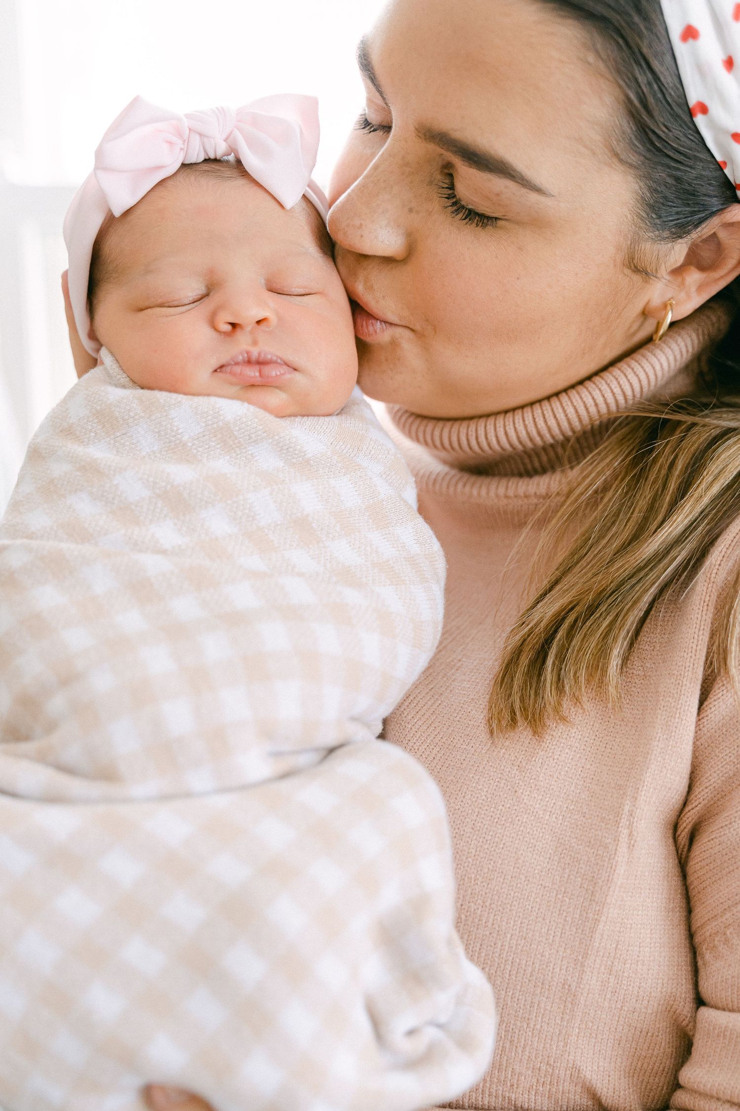 A tender moment captured between parent and baby in soft beige tones showing gentle affection and bonding.