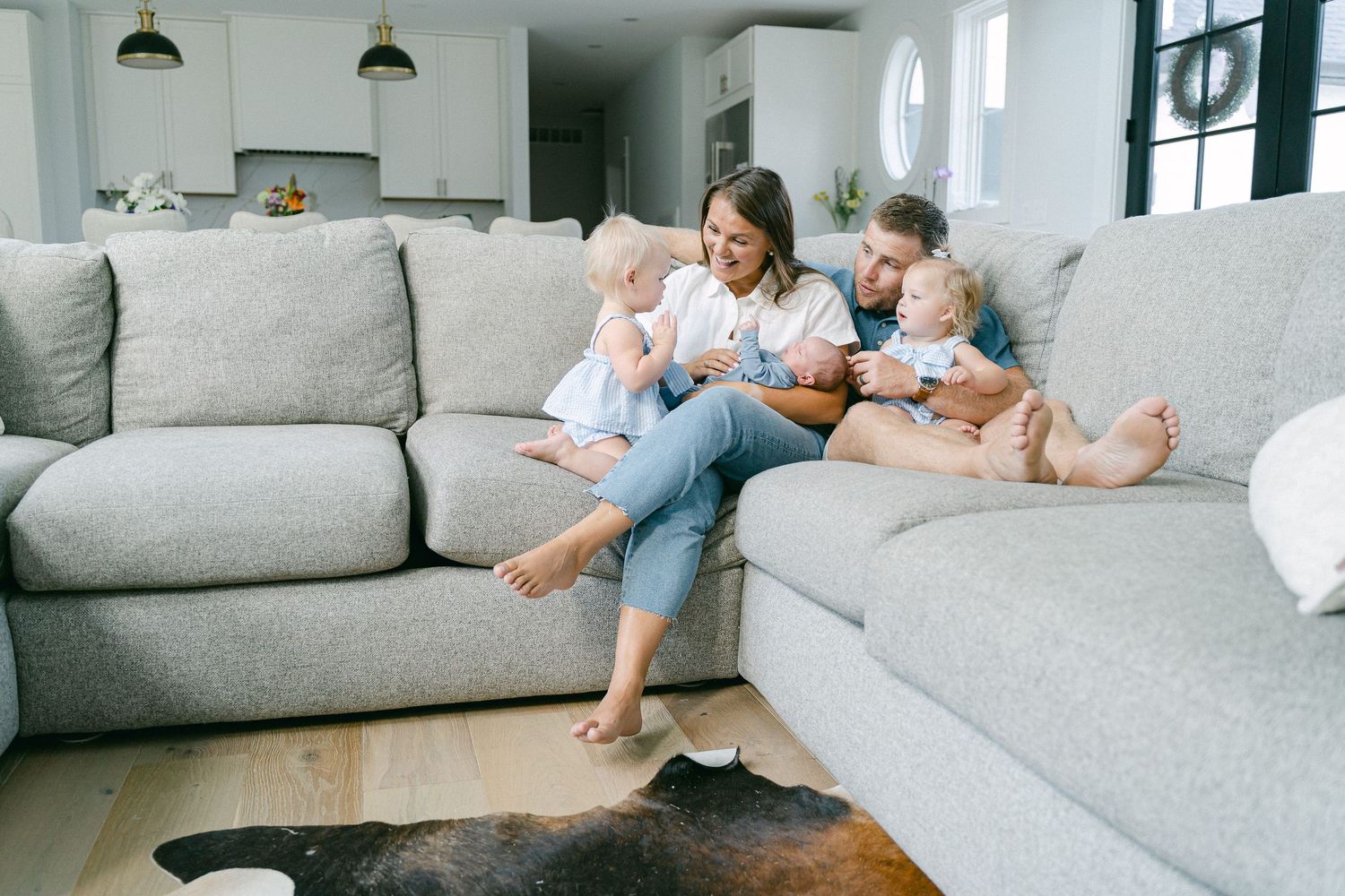 Family relaxing together on comfortable gray sectional sofa in modern living room.