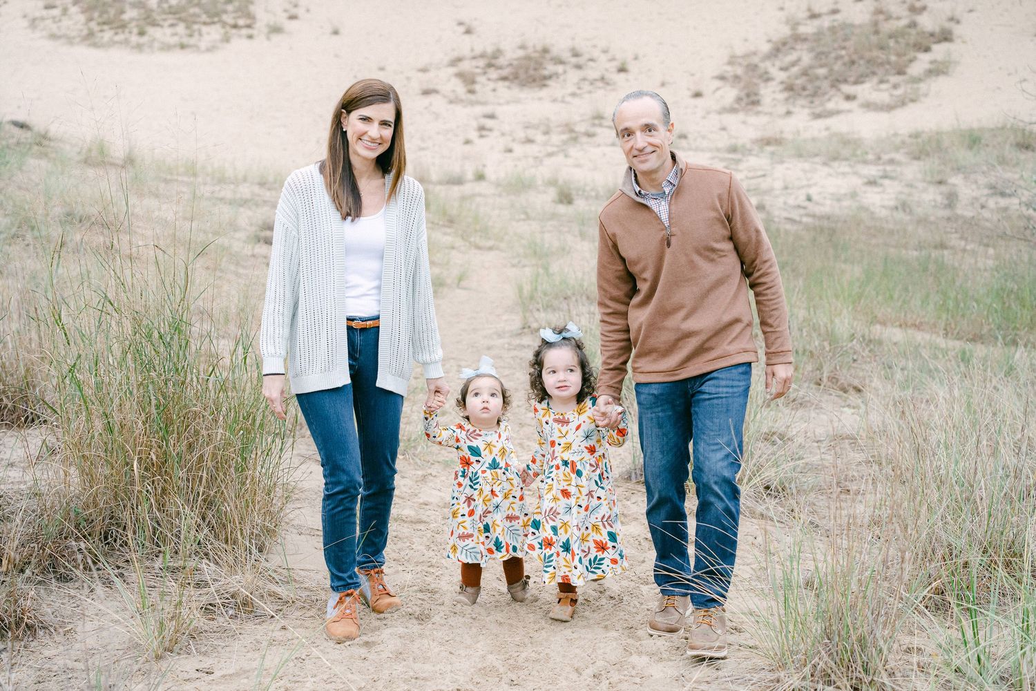A couple walks together on a sandy beach path during a romantic outdoor photoshoot session.