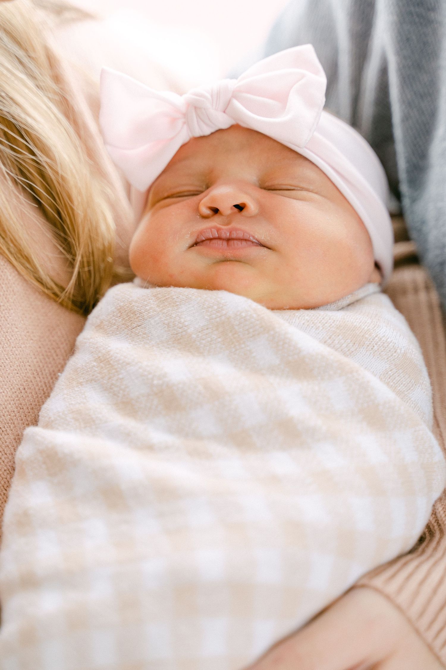 Close-up view of a sleeping newborn baby wrapped in a soft white blanket.